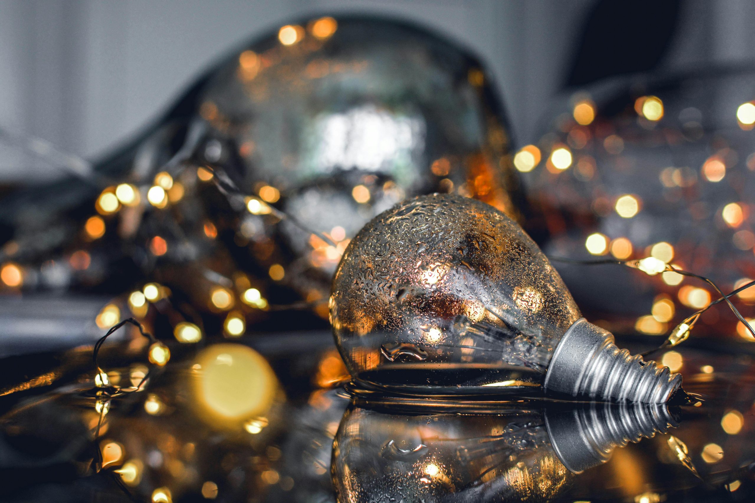 Ampoule posée sur l’eau avec un bokeh photo lumineux en arrière-plan, jeu de lumières et rendu cinéma