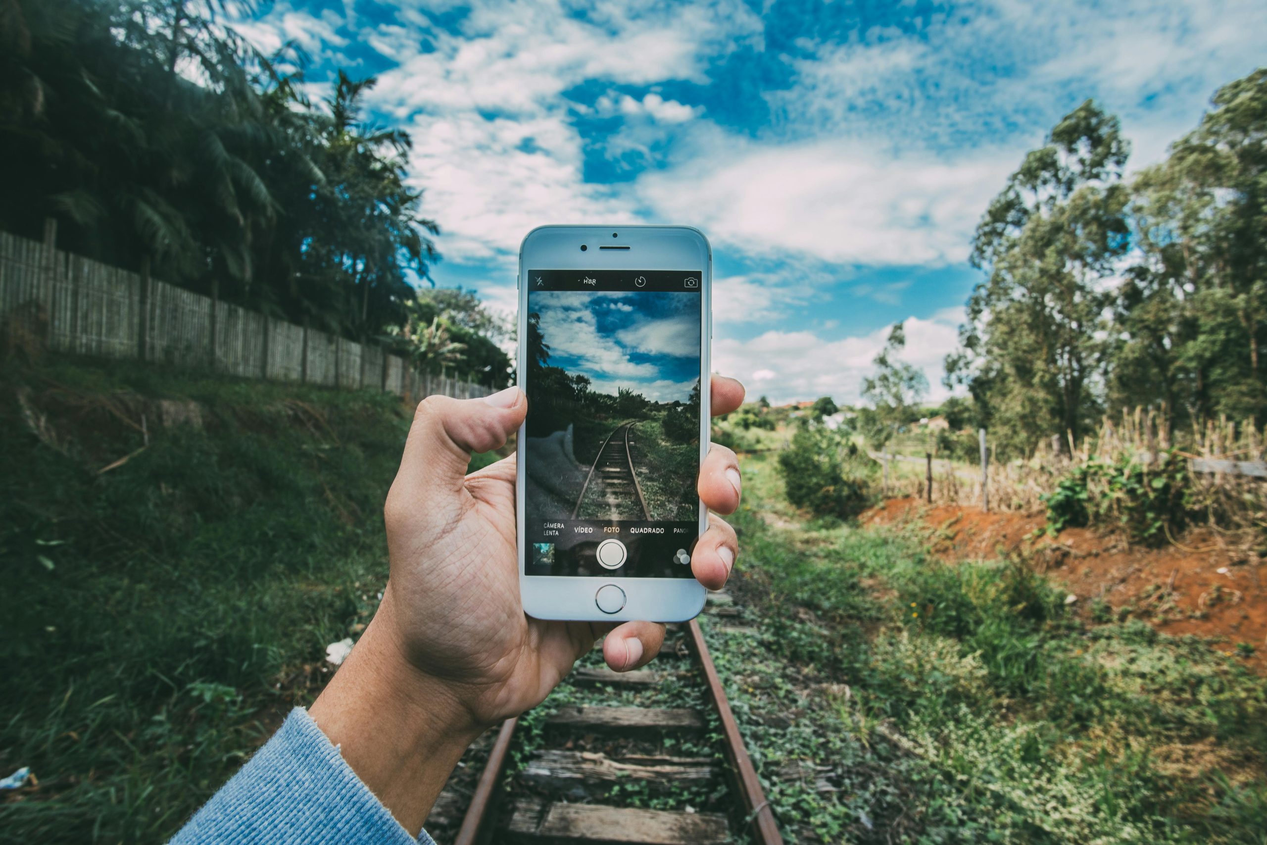 Personne tenant un iPhone pour prendre une photo en extérieur avec un paysage en arrière-plan