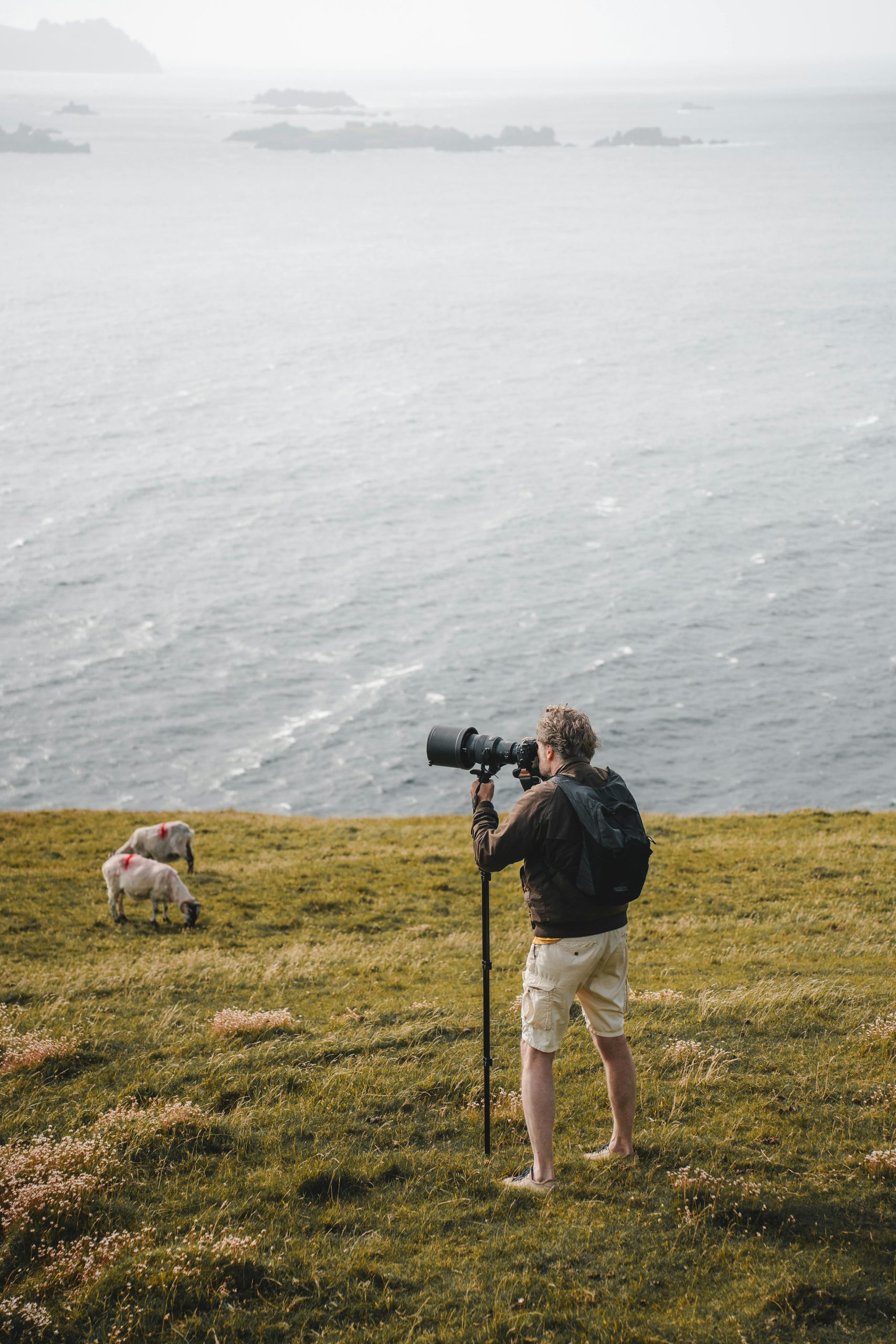 Photographe en extérieur au bord de la mer utilisant un téléobjectif longue focale sur monopode