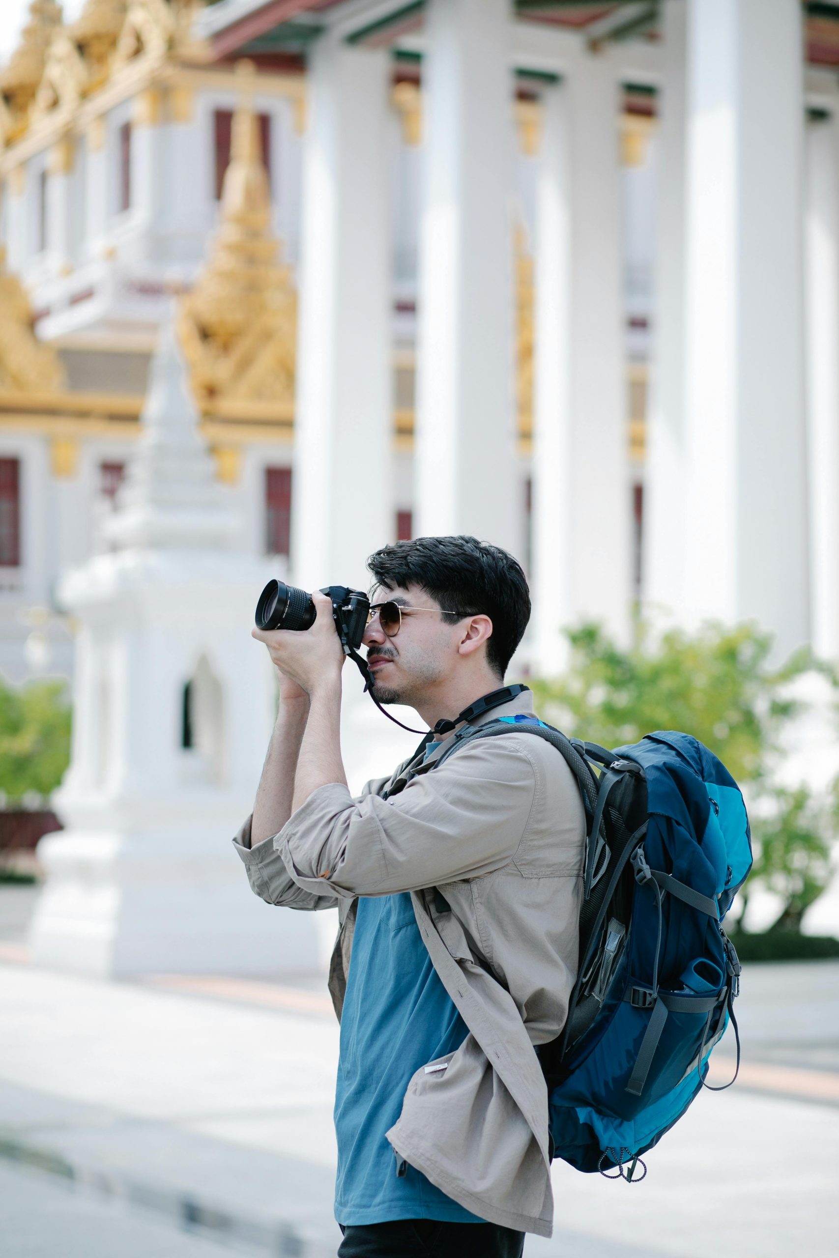 Photographe en voyage avec appareil photo et sac à dos devant un temple, pour illustrer le choix d’un objectif photo voyage