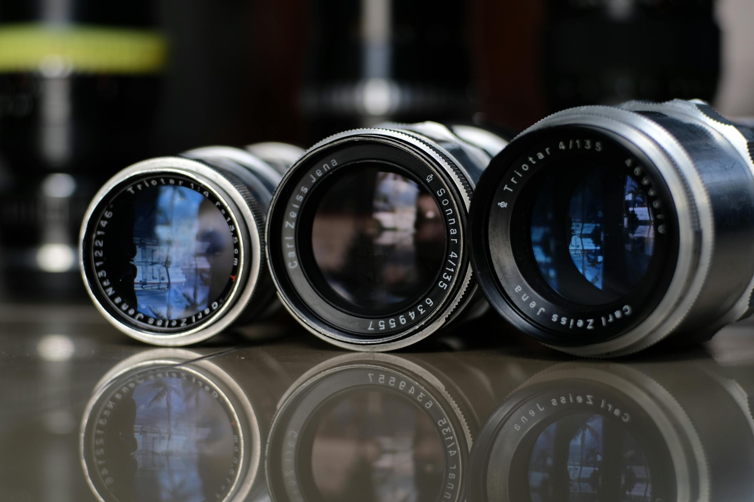 Trois objectifs vintage Carl Zeiss Jena et Triotar alignés sur une table, en gros plan
