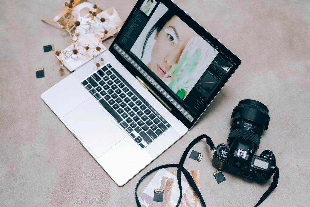 Retouche photo sur ordinateur portable avec appareil photo et objectif à côté