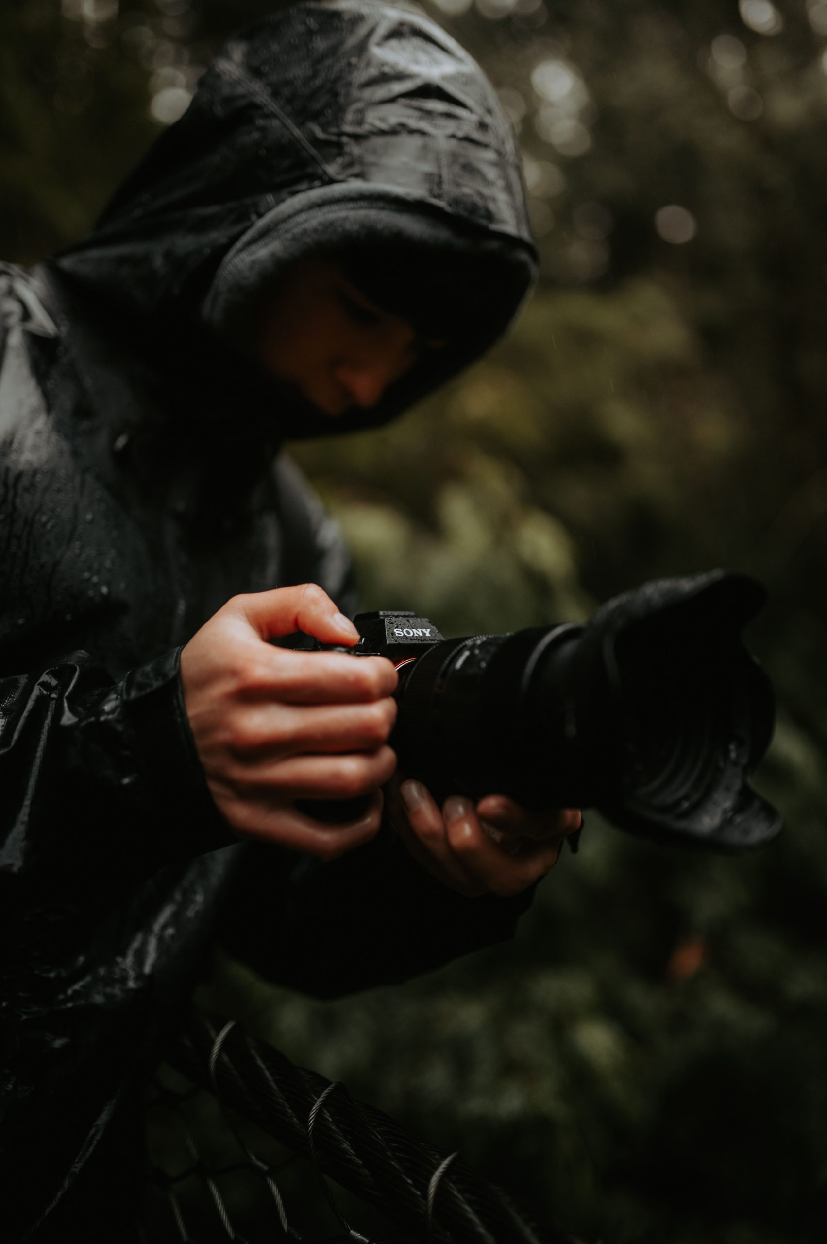 Photographe réglant son appareil photo sous la pluie dans un environnement naturel