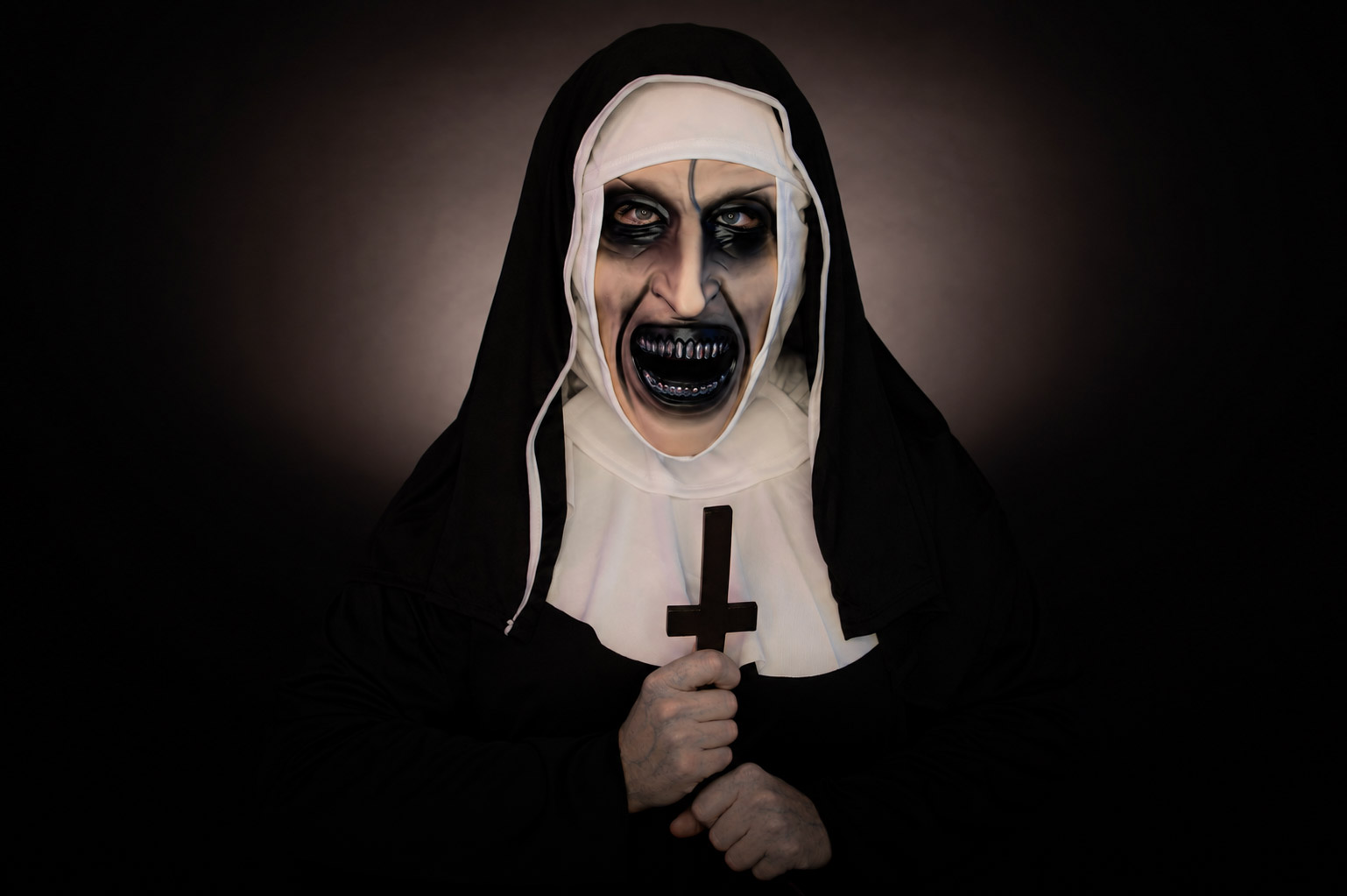 Portrait horrifique d’une nonne démoniaque tenant une croix inversée pour une séance photo Halloween