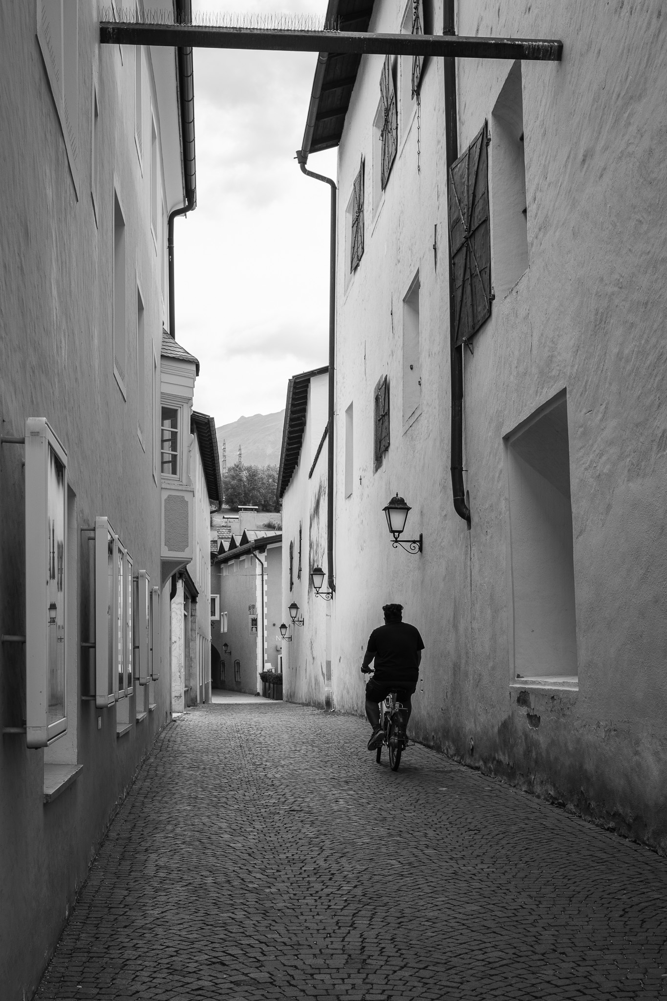 Cycliste dans une ruelle de Vipiteno en noir et blanc photographié au 40 mm